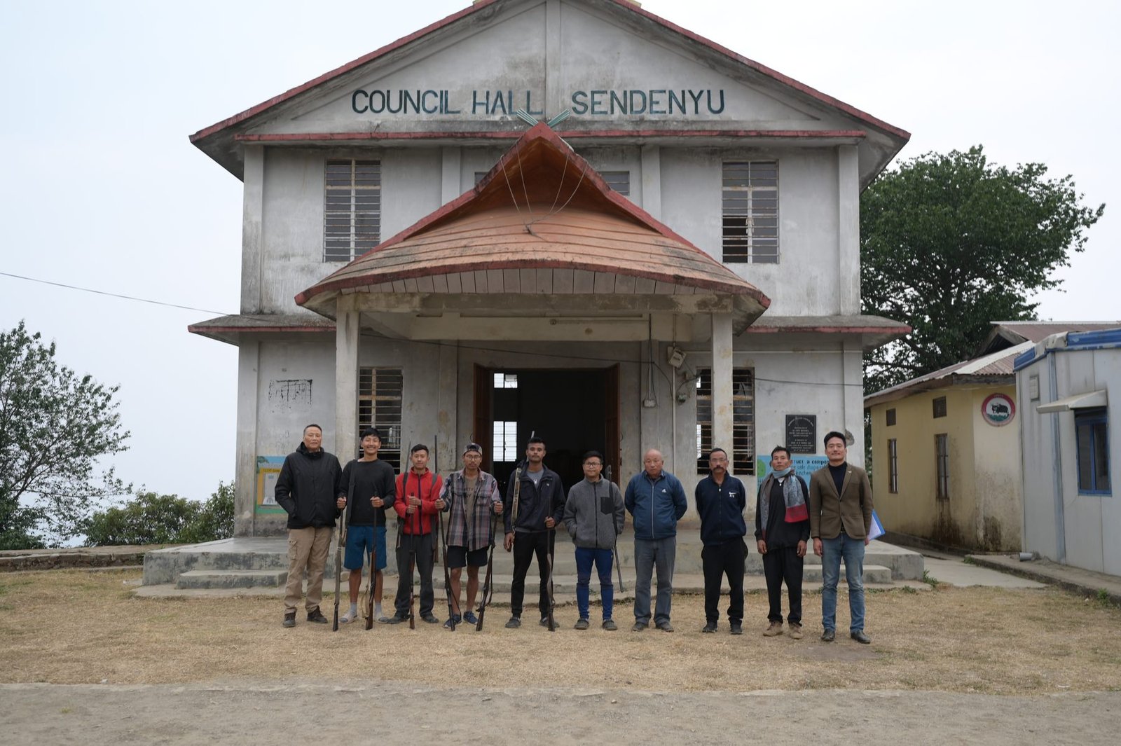 Men standing with guns in front of the Council Hall at Sendenyu