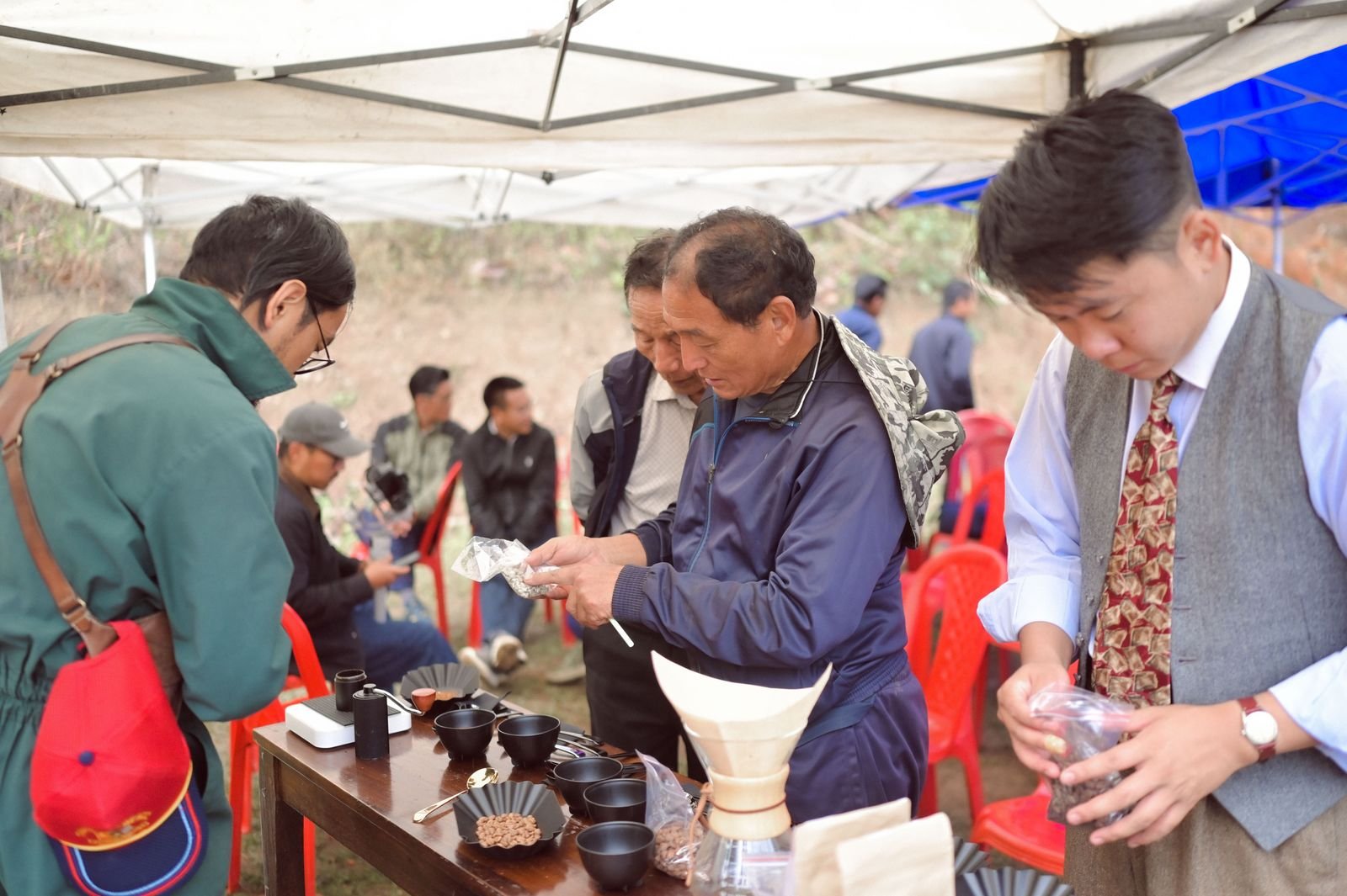 Farmers and visitors examining green and roasted beans at a cupping table
