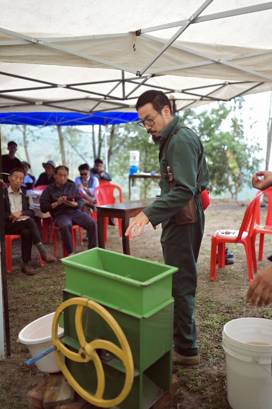 A trainer demonstrating a pulper to seated farmers