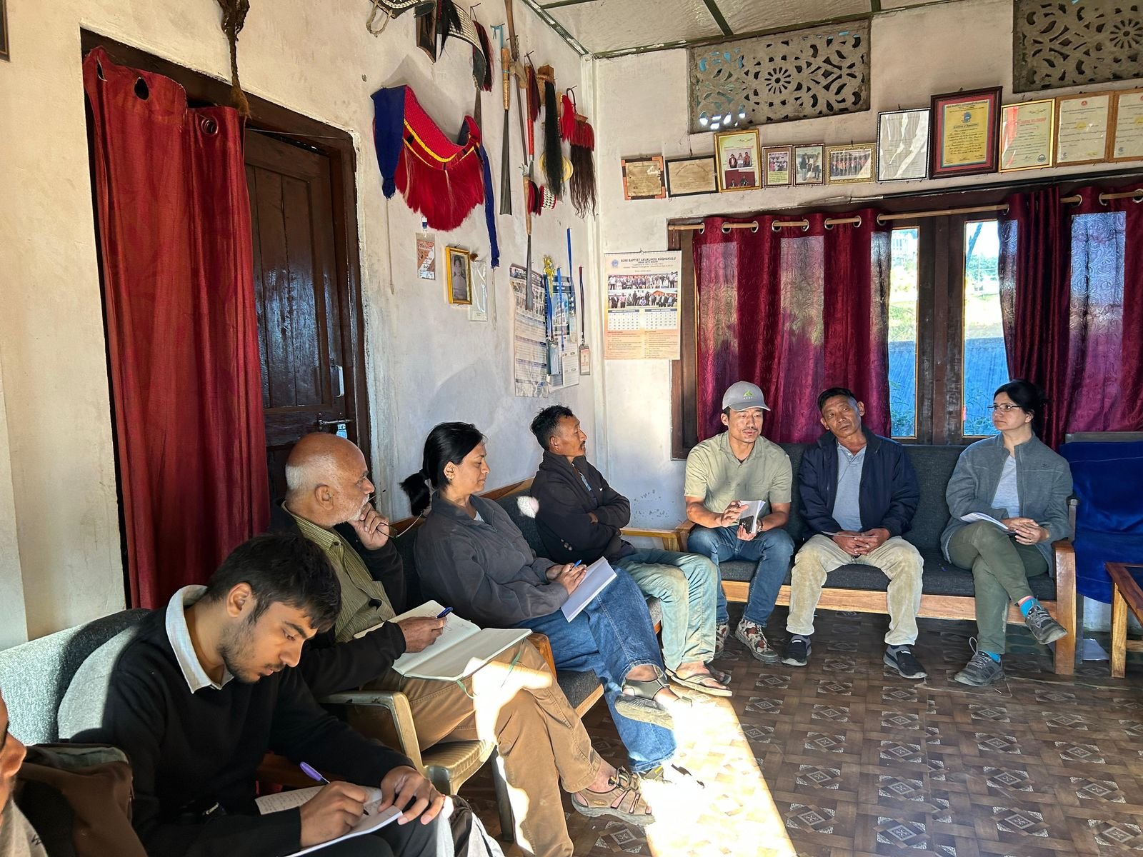 A consultation with village leaders in a home hung with traditional regalia