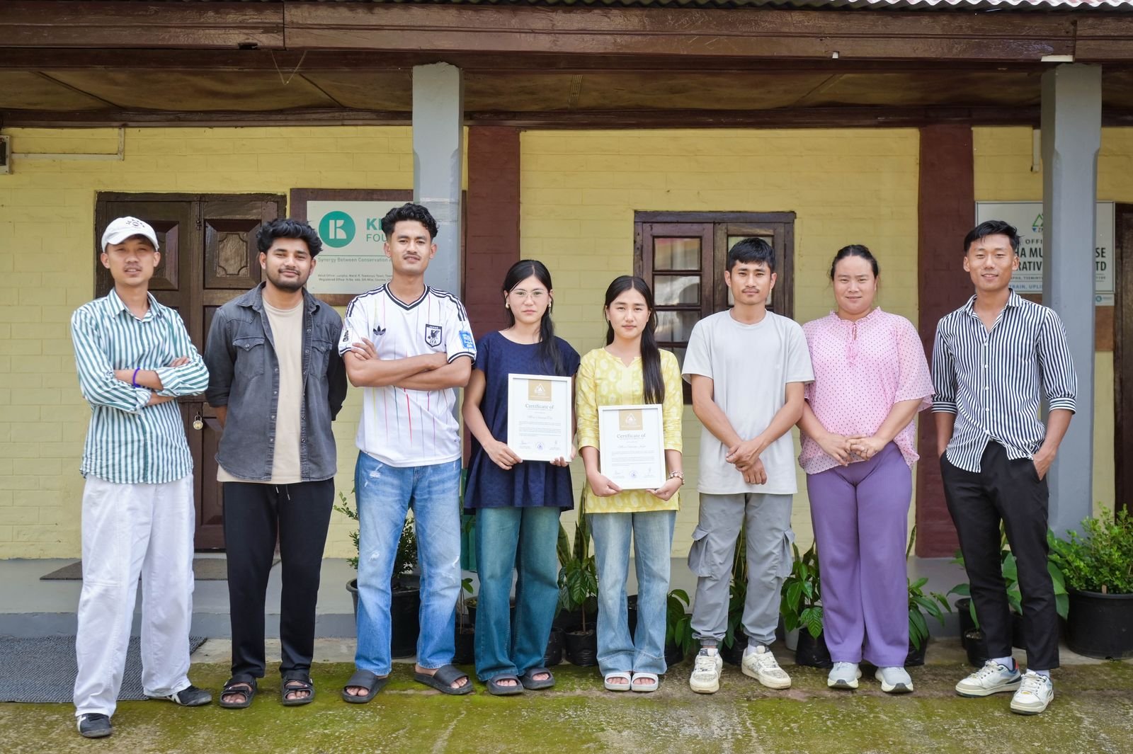 The Artifex Ka team outside the Kenono Foundation office, two holding certificates