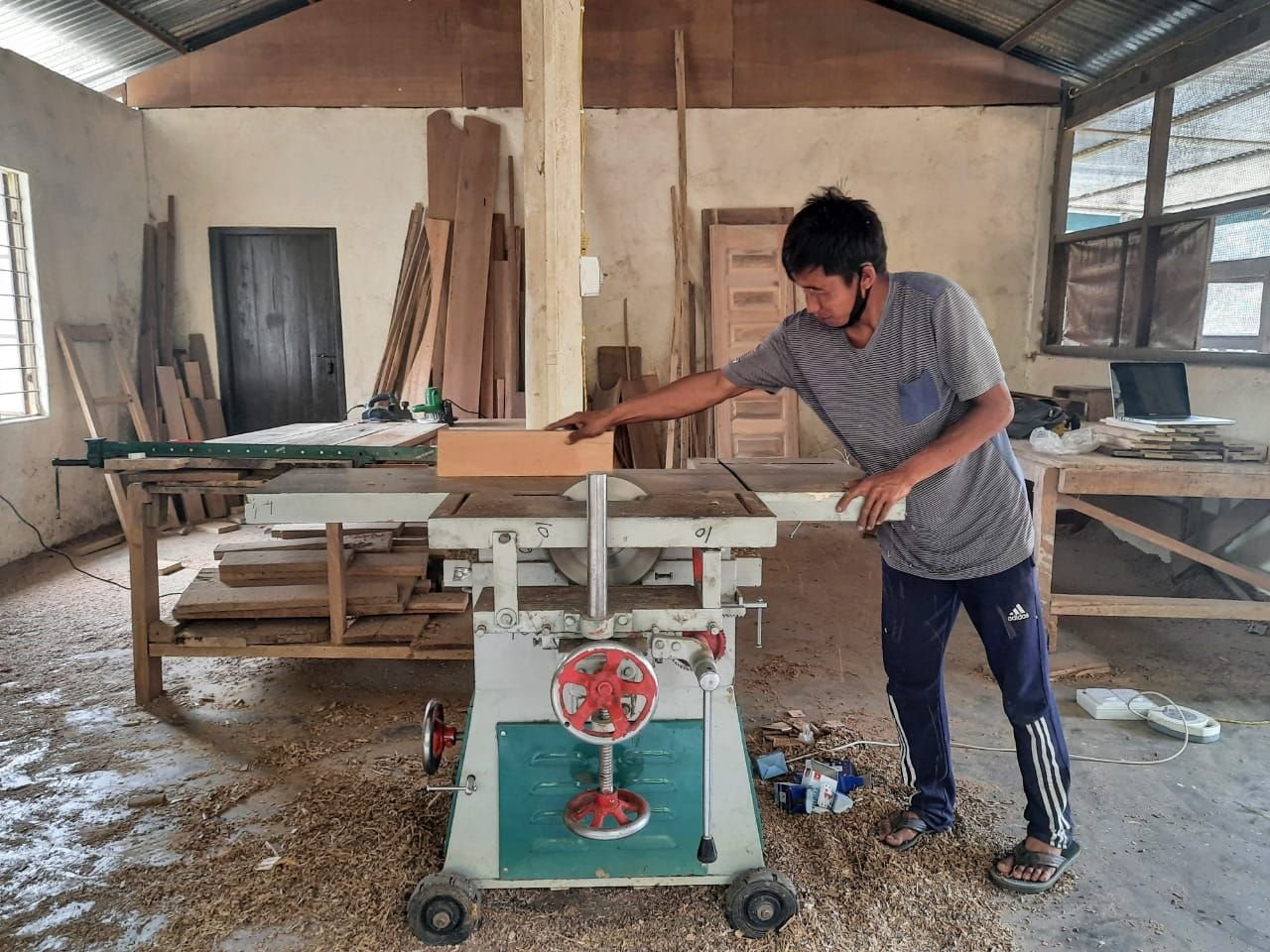 A carpenter guiding a board through the table saw